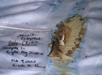 Cotton sheet and underlying mattress scorched where Urandir Oliveira's lower right leg rested on the bed at the time the violet light filled his bedroom around 7 p.m.  on September 15, 2002. To the left is one of my labeled sample collection bags on  February 9, 2003, © 2003 by Linda Moulton Howe.
