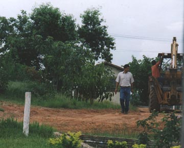 Urandir Oliveira in light shirt next to tractor worker on his Corguinho, Brazil farm.  Urandir purchased 209 acres in 1996. Photograph © 2003 by Linda Moulton Howe.