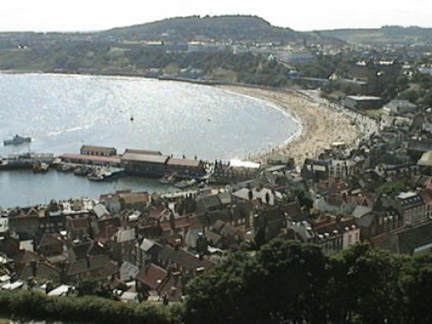 Scarborough is an ancient Bronze Age town on the North Sea coast of North Yorkshire, England, that has had a strong medieval influence, which includes a large 12th Century castle, busy harbor and pier. Image source Wikipedia.