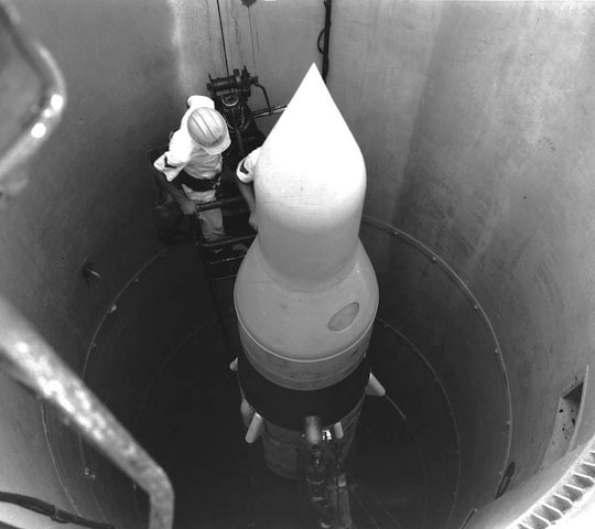 Typical unmanned Minuteman Intercontinental Ballistic Missile (ICBM) Launch Facility. By April 1967, 1,000 Minuteman missiles were emplaced and operational at six sites in seven states. Prior to launch, the 20-ton Launcher Closer covering the missile was blown open with explosive charges. Entrance to the lower equipment rooms surrounding the missile was through the Personnel Access Hatch. The separate Launch Support Building housed electrical equipment, a standby diesel generator, and brine chiller that provided temperature and humidity-controlled air to the launcher. Image source: MinotB52ufo.com.