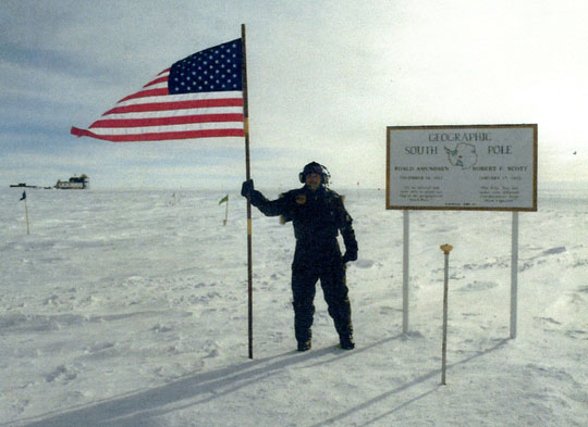 Brian holding U. S. flag next to the metal pole with yellow top that marked the geographic south pole. Image courtesy Brian.