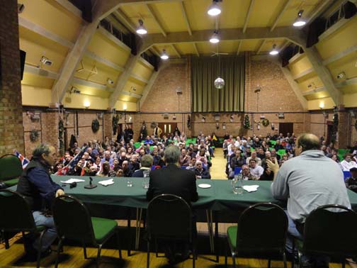 Woodbridge Community Hall gathering about RAF Bentwaters mystery on December 28, 2010, the 30th anniversary of the December 26 - 28, 1980 phenomena. R-L: John Burroughs (table right), former USAF Airman 1st Class at RAF Bentwaters; Nick Pope (center), former U. K. Ministry of Defence UFO desk manager; former USAF Staff Sergeant Jim Penniston (standing below table yellow collar); Peter Robbins, co-author with former USAF Airman Larry Warren of book, Left At East Gate. Image © 2010 by Linda Moulton Howe, speaker and panel member.