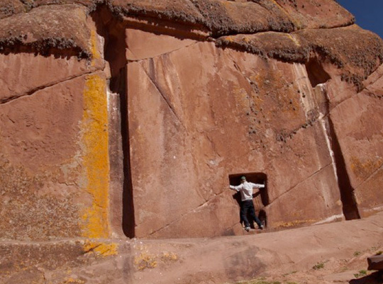The 23-foot-high carved Aramu Muru wall at Lake Titicaca, Peru, contains the solid rock “door” where a man is standing. Jerry Wills kneeled there in November 1998 and his wife saw him disappear and a few minutes later reappear in a flash of light. Jerry thought he had been gone perhaps for hours or days after a discussion in an all-white laboratory with an Intelligent Voice that said our cosmos was the result of that Other Dimension's experiment to simulate a universe.