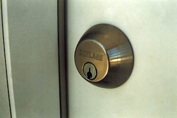  New lock on brand new door surrounded by peeling paint, July 17, 2005.  Photograph © 2005 by Linda Moulton Howe.