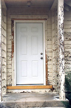 Above: New door and locks surrounded by peeling paint.  Below: Fresh weather caulking on peeling paint around new door, July 17, 2005.  Photograph © 2005 by Linda Moulton Howe.