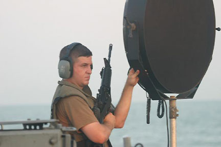 The Long Range Acoustic Device (LRAD) is a sonic weapon developed by LRAD Corporation to send messages, warnings,  and harmful, pain-inducing tones over longer distances than normal  loudspeakers. LRAD Corporation was formerly named American Technology Corporation. In 2004, Carl Gruenler, a former vice president of military  and government operations for American Technology Corporation said that being within 100 meters (330 ft) of the LRAD is extremely painful, and that it was designed for use in short bursts at 300 meters (980 ft),  to give targeted people a headache. He said that “you definitely don't want to be”  within 100 meters (328 feet); the device will cause permanent auditory damage and can damage ear drums within 49 feet (15 meters).  Image of Navy man holding an LRAD weapon on USS Typhoon,  stationed at Naval Amphibious Base Little Creek, January 13, 2006.  Image source: U. S. Navy and Wikipedia.