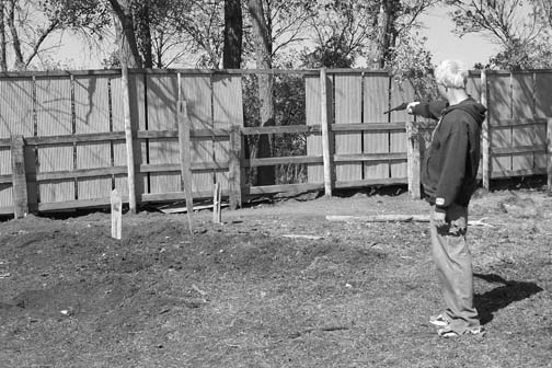 Evan Briese, 16, showing the spot inside the pig corral where he shot the nearest creature with his .22. The three wooden stakes stuck in the ground represent where the entities dragged off the dead sow. At least one of four entities in front of Evan was nearly seven feet all. The missing sheet metal panel was discovered after the encounter and Evan thought it was linked to the actions of the entities. Image © Richard Moss and Lorna Hunter.