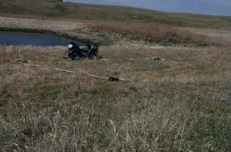 Photograph from east end of water pond looking toward hills where Evan and Buster first looked down on the triangle-shaped craft. Craft location depicted by triangle laid out on grass. Torrey Briese:  "You see those high banks on either side of it (water pond). That’s what they call a spoil pile. It’s the dirt they dug out. The dead cow was to the left out of the picture behind the other spoil pile right behind where the triangular craft set down. " Evan would have been on the hill in upper left corner about 140 yards from craft. Photograph © 2006 Richard Moss and Lorna Hunter.