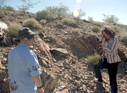 May 30, 2004, at Frenchman Mountain "Vishnu Schist Great Unconformity" east of Las Vegas, Nevada. The rocks are early pre-Cambrian granite and schist that range from .5 billion to 1.7 billion years old. On left, Dan Burisch, Ph.D., microbiologist, videotaped by Linda Moulton Howe. Photograph © 2004 by Winston Smith.