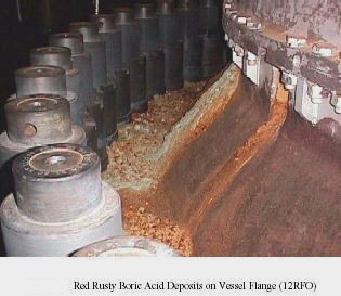 Above: Top bolted domed head to nuclear reactor vessel at Davis-Besse Nuclear Power Station in April 2000. Red streams running down the side toward 25-inch-long grey bolts are from boric acid leaking from the large hole eaten away into the steel under Nozzle 3. The Nuclear Regulatory Commission at first denied this revealing photograph had been given to the NRC by Davis-Besse owners. Below: Boric acid also caused red stains at Nozzle # 1 beneath the dome on Vessel Flange (12RFO) shown above. Photographs by Nuclear Regulatory Commission.
