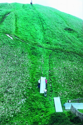 Britain's National Trust hauls metal roofing up 130 foot high Silbury Hill to cover hole that suddenly emerged in the top on May 29, 2000. Photograph © 2000 Wiltshire Gazettte and Herald. 