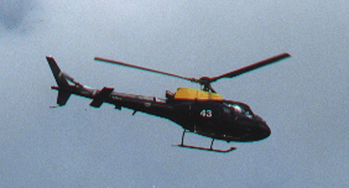 British Army helicopter with yellow top and belly identified only as "43" flying with three other similar helicopters between East Field, West Stowell/Oare, Pickled Hill and Woodborough Hill on August 3, 2000. Photograph © 2000 by Linda Moulton Howe.