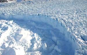 Calving front, or break-off point into the ocean, of this Helhiem Glacier located in southeast Greenland. The image, taken in May 2005, shows high calving activity associated  with faster glacial flow. This glacier is now one of the fastest moving glaciers in the world. Image credit: NASA/Wallops.