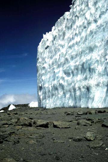 Above: The margin, or edge, of the Furtwangler Glacier atop Kilimanjaro's summit as it looked in 2000. Below: 2006 image shows the retreat of the massive ice field. Rocks in front of tripod were against ice wall in 2000. Since then, the ice wall has shrunk back as much as 5 meters (16.5 feet). Photos courtesy of Lonnie Thompson, OSU.
