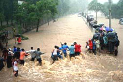 July 27, 2005, Mumbai (Bombay), India. After 37.1 inches fell the previous day, people used ropes to move in the flooded streets. R. V. Sharma, Director of the Meteorological Department in Mumbai, said: "Most places in India don't receive this kind of rainfall in a year. This is the highest ever recorded in India's history." Image © 2005 by AP.