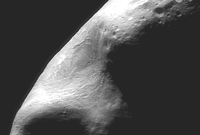 February 15, 2000 photograph while the NEAR satellite was passing directly over the large gouge "saddle" that is surprisingly smooth and free of craters. Detail down to 120 feet (35 meters) across. Narrow parallel troughs closely follow the shape of the saddle gouge. Photograph courtesy Johns Hopkins University Applied Physics Laboratory, Laurel, Maryland.