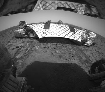On January 15, 2004, at 3 a.m. ET, NASA's Spirit land rover finally moved out from its air bag-shrouded lander leaving tracks on the Martian soil of the Gusev crater. Image credit: NASA/JPL.