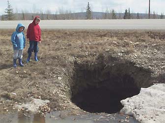 This sink hole recently near Fairbanks, Alaska, formed due to the melting of a large ice pocket within permafrost that is gradually thawing as temperatures warm. Photo courtesy Vladimir Romanovsky, Geophysical Institute, University of Alaska Fairbanks.