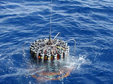 Prof. Sabine: "This is a picture of the sampling device we used to collect water samples from all depths in the ocean. The long grey cylinders can be closed at any depth we choose using an onboard computer." Photograph © 2004 by Christopher L. Sabine, NOAA and Univ. of Washington.