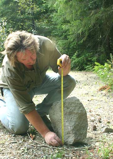 Richard Noll measuring height of upturned rock found in Cascade mountain camp site in August 2005. Photograph © 2005 by Richard Noll.