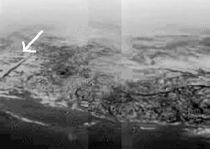 Dark "channels," perhaps draining down into dark "methane sea" at bottom, in image taken from about 8 kilometers altitude by Huygens probe with a resolution of about 20 meters per pixel. Boundary between high, lighter-colored terrain and and darker lowland area on Titan resembles a coast line. One of the many mysteries: what is the right angle structure beneath the white arrow? This composite was produced from images returned January 14, 2005, by ESA's Huygens probe. Image source: ESA/NASA/JPL/University of Arizona.