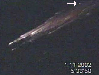 Video frame from a 22-second sequence taped at 5:38:58 a.m. on November 1, 2002, by Halil Yalcin while driving with his wife between Balikesir and Susurluk, Turkey. The white arrow points at the yellow-colored light that many witnesses over many kilometers said pulsed in a stationary position while a bright, white light nearby broke up into many large pieces that are shown falling through the frame. Videotape © 2002 by Halil Yalcin and provided by the Turkish Sirius UFO Space Sciences Research Center and International UFO Museum, Istanbul. Actual videotape can be seen at website linked at bottom of this report.