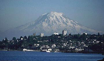 Moderately active volcano, Mount Rainier, looms in the background of Tacoma, Washington, population 194,000. Its last major eruption was 500 years ago. Photograph by Lyn Topinka, U. S. Geological Survey.