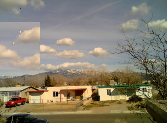 On February 26, 2010, at 2:44 PM Mountain in Albuquerque, New Mexico, Alan Ramon took this photograph from his home rooftop looking east towards the Sandia Mountains. At the time, he did not see with his eyes the three, white objects in formation [ blown up in inset ] or the dark object in upper left corner. Alan took image with his Del laptop that has built in lid-camera that operates at about 1/30th of a second. Image © 2010 by Alan Ramon. 