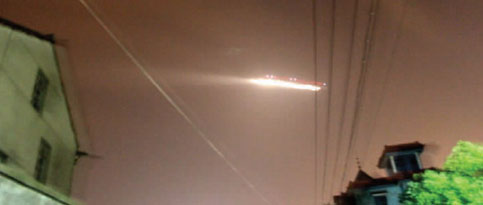 Photo taken by a Hangzhou resident shows an unidentified flying object hovering over Hangzhou, capital of East China's Zhejiang province, around 9 PM, Wednesday, July 7, 2010. Note the three-sphere lightning rod used only in Hangzhou, China, rising from lower right roof. See People's Daily Online.