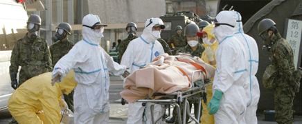 A person who is believed to be radiation-contaminated is wheeled on a guerney to a radiation-treatment center. Photo: Jiji Press/AFP.