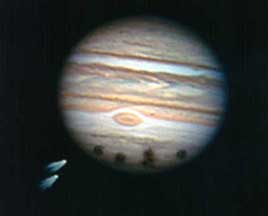 On lower left are two of the twenty-one comet fragments that impacted Jupiter's atmosphere leaving dark holes on July 16 to 22, 1994. Each impact mark is larger than Earth. This event was the only time in human history that comet fragment collisions with a planet has been witnessed and photographed. Image © 1994 by John Chumack, Galactic Images.