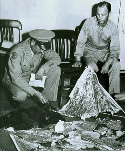 July 9, 1947, Commanding General of the Eighth Air Force Roger M. Ramey and Gen. Ramey's Chief of Staff, Col. Thomas DuBose, gathered weather balloon debris in a Roswell Army Air Field office for a phony counterintelligence presentation to media to divert public attention from the truth: that non-human craft came down between Corona and Roswell and non-human bodies were retrieved. In this famous photo by J. Bond Johnson, Brig. Gen. Roger Ramey is seen making the case that the debris found near Roswell was really just that of a fallen weather balloon. The Washington Post on July 9, 1947, ran an article using the photo, with the caption, “In Fort Worth, Tex., Gen. R. M. Ramey (left) and Col. T. J. Dubose examine high altitude weather device, mistaken for a flying disc.”