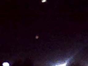 Cropped cell phone image showing two of three strange lights (middle reddish and top white), first lined up horizontally and then rotated counterclockwise to a vertical line above Henderson Junior High football field (bottom two stadium lights). Cell phone image taken on Thursday, October 23, 2008, 8:34 PM Central, from parking lot of Gilbert Intermediate School on Frey Street near Henderson in Stephenville, Texas. Image © 2008 by Brent Chambers.