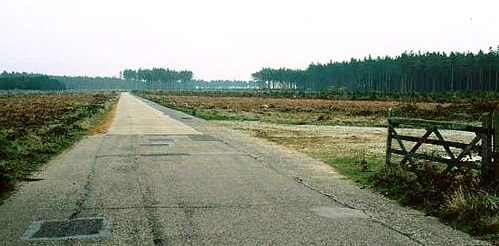 East Gate at RAF Woodbridge open with road and Rendlesham Forest beyond.