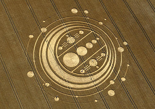 Rain was heavy in Wiltshire County, England, even flooding roads, the first week of August 2009. But at Windmill Hill near Avebury Trusloe, a 350-foot-diameter pattern of circles on rings with complex dumbbells in the center was reported on August 6. Aerial image © 2009 by Frank Laumen, VisibleSigns.de.   More information and images: Cropcircleconnector.com.