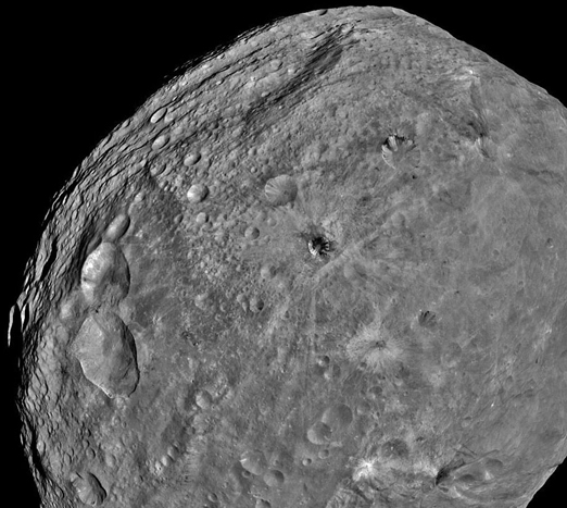 Northern half of asteroid Vesta between Mars and Jupiter is more heavily cratered than the south and no one knows why. Image above of the 310-diameter Vesta (500 km) was taken by NASA's Dawn spacecraft on July 24, 2011, after entering into orbit around Vesta on July 15, 2011. Dawn is the first Earth robotic spacecraft to orbit Vesta, the second largest object in the asteroid belt. Also unknown is what makes the dark streaks in some of Vesta's craters such as the crater near image center? Or what makes the grooves that circle the asteroid nears its equator? 2011 image by NASA and JPL-Caltech.