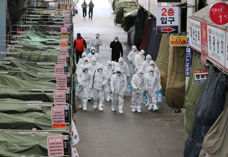 Hazmat-clothed workers are spraying disinfectant in a Daegu, South Korean market on February 23, 2020, after the COVID-19 dangerous coronavirus has been confirmed there. This date, confirmed infections jumped to 763 and 6 deaths. More than half of the confirmed cases are members of the Shincheonji Church of Jesus. Along with South Korea, there have been sudden jumps in confirmed COVID19 cases in Italy and Iran. The World Health Organization is warning African leaders to prepare for the dangerous coronavirus's invasion in 13 African countries that employ Chinese mining and other migrant workers. Image by Yonhap/ Agence France-Presse/ Getty Images.