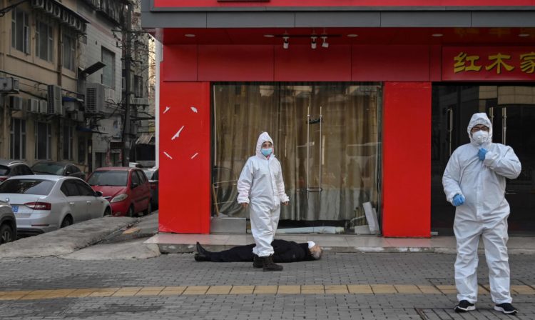 After a Wuhan, China, male resident collapsed and died on the street Thursday, January 30, 2020, emergency workers garbed in white suits and virus-protection masks arrived and his death was later confirmed as pneumonia from the coronavirus. Image by The Guardian.