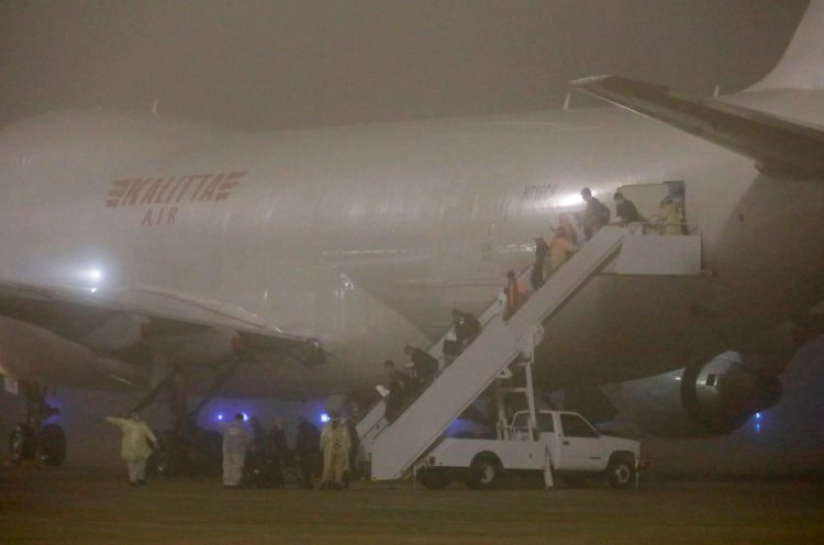 Early Monday morning arrival of chartered flight to Lackland AFB in San Antonio, Texas, of some 300 Americans evacuated from the Diamond Princess cruise ship that has been quarantined in Yokohama, Japan, since early February. Fourteen of the passengers, who had been free of symptoms, were confirmed to be infected with COVID-19 coronavirus right before the flight left Japan. Now those fourteen will be isolated again in quarantine with American medical care. Image by Edward Ornelas, Getty Images.