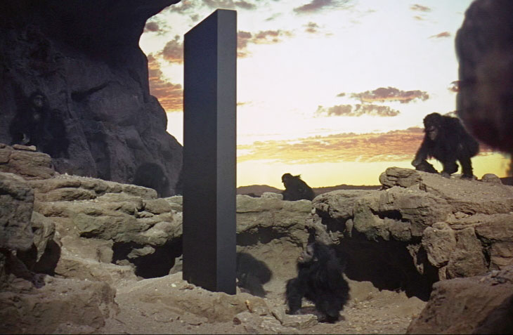 Original frame from 1968 science fiction epic film by famed director Stanley Kubrick entitled "2001: A Space Odyssey." The story centers around a large, perfectly machined monolith presumed to have been made by an unseen extraterrestrial species. Multiple versions of the monolith were placed periodically in key times and places in the evolution of Homo sapiens sapiens, beginning in Africa after already-evolving primates were manipulated genetically to become humanity. Image source Wikipedia.